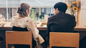 a man and a woman sitting at a table in front of a window