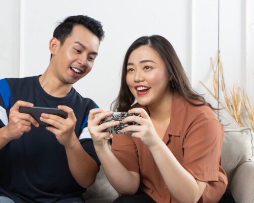 a man and woman sitting on a couch looking at a cell phone