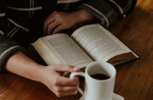 A person sitting on the floor with a book and a cup of coffee