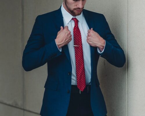 a man in a suit and red tie tying his tie